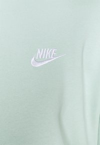 Ljusgrön Nike-tröja med en slät yta. Har en broderad vit logotyp på vänstra bröstområdet. Klassisk rund halsdesign.