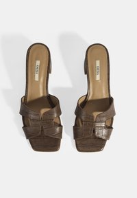 Brown leather heeled sandals featuring a crocodile texture, open toe, two front straps, and a square-shaped toe box. Label "DESA" visible.