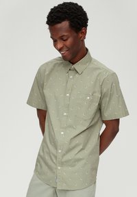 Hellgrünes Kurzarmhemd mit Button-Down-Kragen, das ein kleines Blumenmuster und eine Brusttasche aufweist. Strukturierter Stoff.