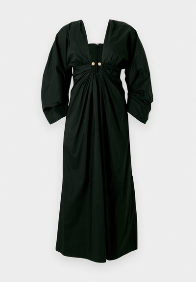 Juodas suknelė su giliais V formos iškirpimu, surinkta liemeniu ir didelėmis rankovėmis. Su užpakaline užtrauktuku ir dviem aukso spalvos mygtukais priekyje.