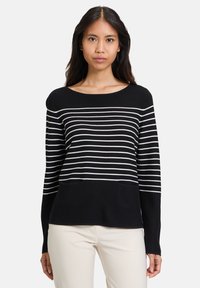 Schwarzer Pullover mit weißen horizontalen Streifen, rundem Ausschnitt, langen Ärmeln und zwei vorderen Taschen. Glatter Strickstoff.