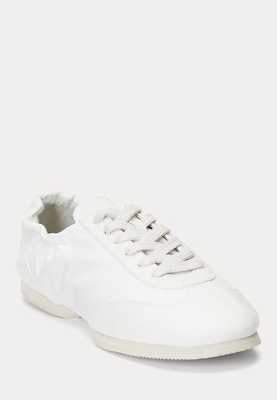 Balti sportiniai batai su elastingu kulkšnies apvadu, audinio viršumi ir baltais batraiščiais, šiek tiek pasuktas vaizdas ant vienspalvio fono.