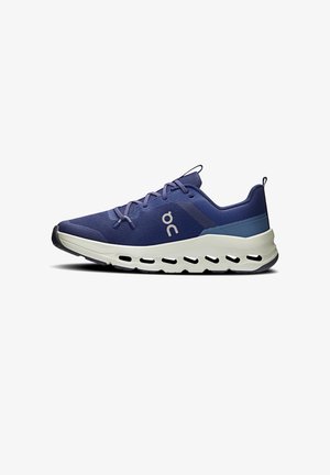 Chaussure de sport bleue avec tige en mesh et design superposé. Dispose d'un logo proéminent, d'un système de laçage et d'une semelle extérieure blanche amortie avec des trous de ventilation.