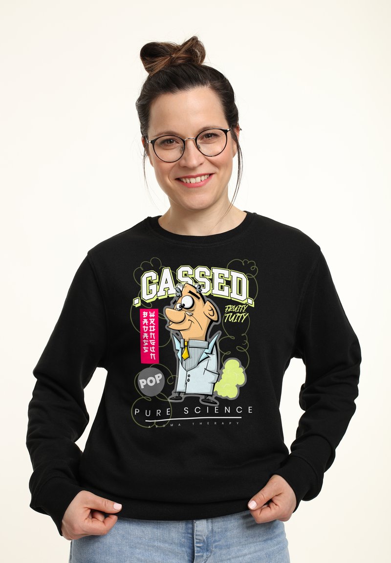Svart sweatshirt med en tecknad grafik som föreställer en karaktär i labbrock, gul slips och texten "GASSED" i fet grön och rosa.