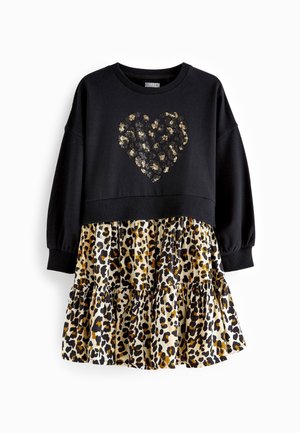 Vestido negro de manga larga con un corazón de lentejuelas doradas y negras en el pecho y una falda con volantes y estampado de leopardo.