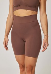 Brązowe, wysokie szorty z teksturowanego, elastycznego materiału. Projekt cechuje bezszwowy pas i długość do połowy uda dla wygody.