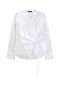 Biała koszula z długim rękawem z gładkiego materiału, z okrągłym dekoltem i asymetrycznymi marszczeniami zapinanymi na tasiemkę w talii.