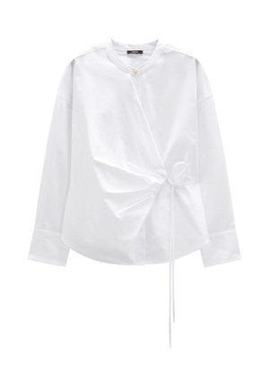 Biała koszula z długim rękawem z gładkiego materiału, z okrągłym dekoltem i asymetrycznymi marszczeniami zapinanymi na tasiemkę w talii.