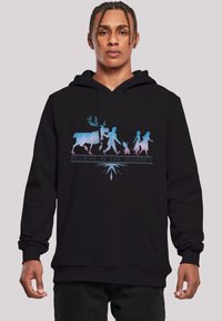 Felpa nera con cappuccio caratterizzata da un grafico multicolore di una scena in silhouette con un renna, figure, e il testo "Credi nel Viaggio."