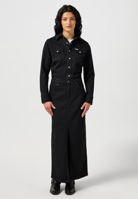 Czarna sukienka dżinsowa z guzikami na górze w stylu koszuli, z kieszeniami oraz długą, dopasowaną spódnicą z bocznym rozcięciem. Gładka tekstura z minimalnymi akcentami.