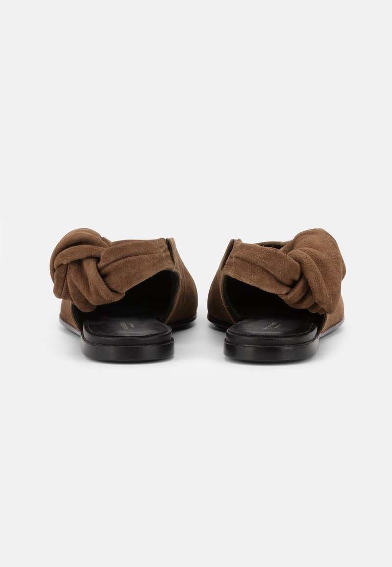 Braune flache Sandalen aus Wildleder mit geknoteten Riemen und schwarzen Fußbetten, von hinten auf weißem Hintergrund gezeigt.