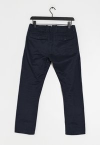 Námorně modré kalhoty vyrobené z látky s hladkým povrchem. Obsahují dvě zadní kapsy s knoflíkovým zapínáním a rovné nohavice.