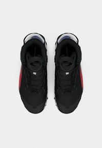 O pereche de pantofi de drumeție Salomon negri și roșii, văzuți din sus, pe un fundal alb.