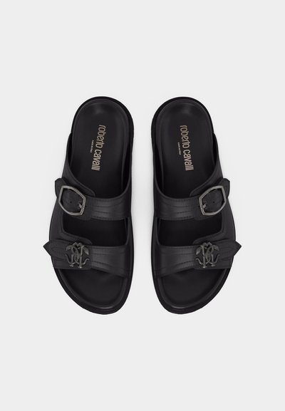 Sandales en cuir noir avec doubles brides, boucles métalliques et logo avec initiales sur les brides avant, marquées "roberto cavalli" à l'intérieur des semelles.