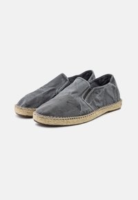 Scarpe slip-on grigie con tomaia in tessuto morbido e suola in corda di juta. Presentano pannelli laterali elastici per una facile calzata e una finitura liscia e testurizzata.