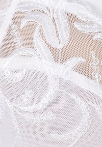 Witte geborduurde kant met bloemmotieven, met een delicate open weefstructuur. Het ontwerp bevat ingewikkelde details van bladeren en stelen.