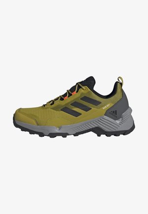 Chaussure de trail running Adidas verte et grise avec des bandes noires, une semelle robuste et des accents orange sur les lacets.