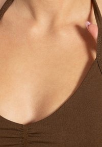 Top de tela marrón ajustado con escote en V y detalles fruncidos en el centro. Textura suave con tirantes finos.