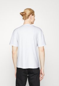 Camiseta de algodón blanca con mangas cortas, cuello redondo y un corte relajado. Diseño liso, sin patrones ni acentos visibles.