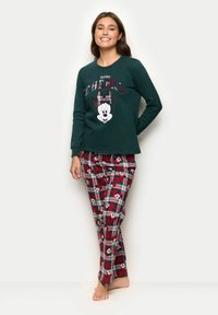 Zelený pyžamový top s dlouhým rukávem s nápisem "Holiday Cheers" a grafikou Mickey Mouse. Červené kárované kalhoty s malými ikonami Mickeyho na bílém pozadí.