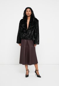 Giacca in pelliccia sintetica nera con ampio colletto, abbinata a una gonna in pelle bordeaux di lunghezza media e scarpe con tacco nere. Design semplice ed elegante.
