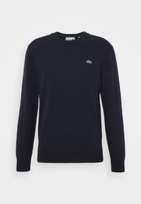 Navyblauer langärmeliger Rundhals-Pullover mit grünem Krokodil-Logo von Lacoste auf der linken Brust sowie gerippten Bündchen und Saum.