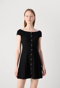 Robe noire décolletée avec texture côtelée, dotée d'une jupe évasée et de boutons dorés sur le devant. Design simple et élégant.