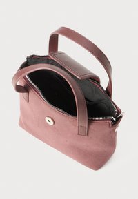 Small mauve suede handbag with two leather handles, a top zipper partially open, and a black interior lining visible.