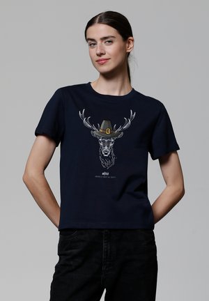 T-shirt en coton bleu marine à manches courtes présentant un graphique d'un cerf avec des bois portant un chapeau, imprimé en blanc et marron.