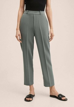 Kobieta nosząca szare spodnie o prostych nogawkach z wysokim stanem i szlufkami na pasek, w połączeniu z czarnymi plecionymi sandałkami wsuwanymi oraz czarną, bezrękawną bluzką.