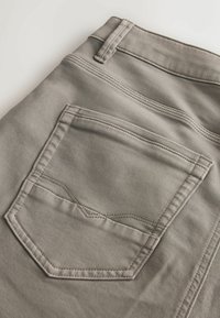 Hallide kangaga värvitud püksijalg, millel on taga tasku, silmapaistva niidiõmblusega ja määratletud tasku kuju. Sile tekstuur ja viimistletud disainiparameetrid.