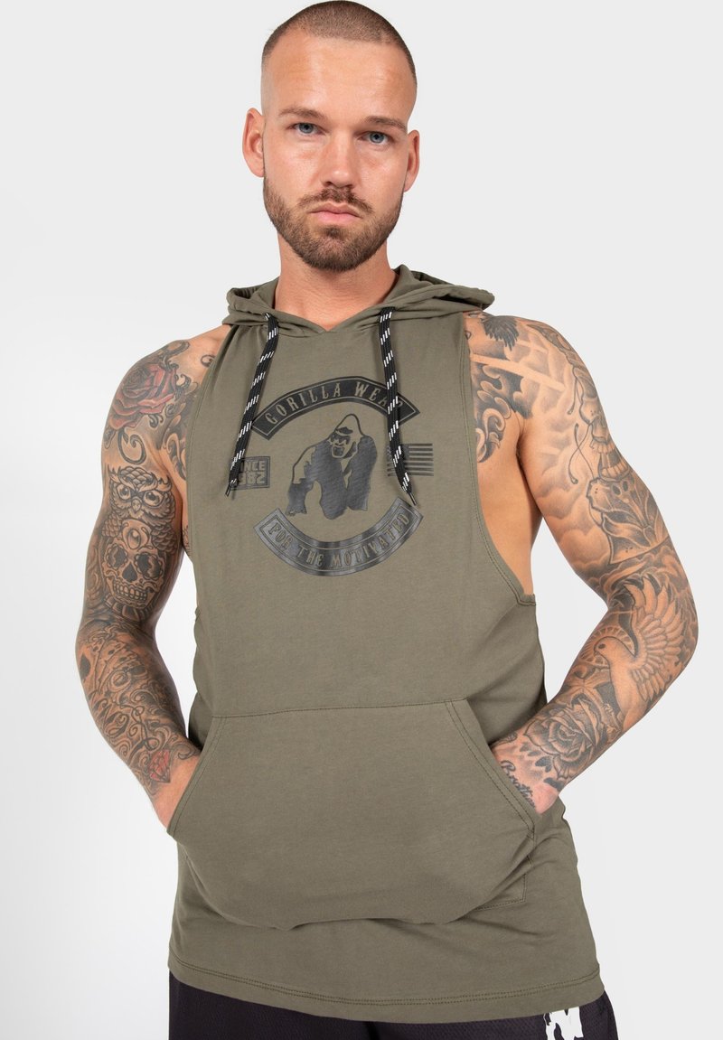 Olivegrüner ärmelloser Hoodie mit großem schwarzem Grafiklogo, vorderer Tasche, verstellbaren Kordeln und auffälligen Tattoo-Details an den Armen.