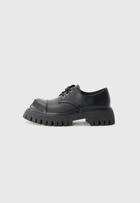 Scarpe nere stringate con punta arrotondata, suola spessa in gomma e grande motivo di battistrada. Realizzate in pelle liscia con cuciture a contrasto.