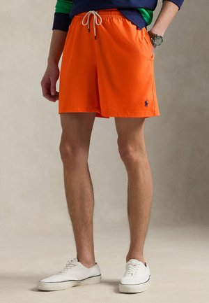 Jasnopomarańczowe kąpielówki z elastycznym pasem, regulowanym sznurkiem i małym niebieskim logo. Miękki, lekki materiał.