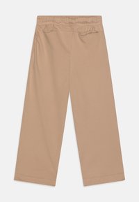 Béžové kalhoty s širokými nohavicemi vyrobené z měkké bavlny, s elastickým pasem a dvěma bočními kapsami, s hladkou texturou a jednoduchým designem.
