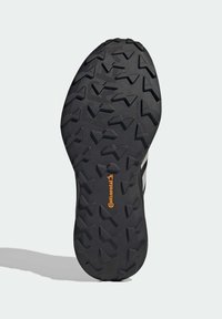 Semelle de chaussure en caoutchouc noir avec un motif de semelle angulaire et profond pour une meilleure adhérence. Présente le logo orange "Continental" près du centre.