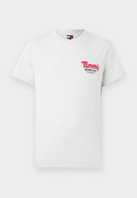 T-shirt blanc à manches courtes avec un col ras du cou, portant un petit logo rouge et noir "Tommy Jeans, N.Y." sur la poitrine gauche.