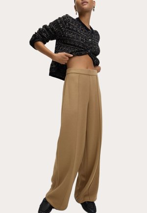 Schwarze Strickjacke mit Knöpfen, kombiniert mit beigen, weitgeschnittenen Hosen mit vorderen Bügelfalten. Texturiert, lässige Passform, entspannte Styling.