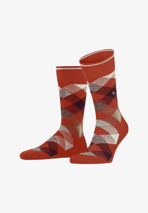 Une paire de chaussettes mi-mollet avec un motif en losanges argyle rouge, beige, noir et blanc, et une fine rayure blanche près du haut du bord.