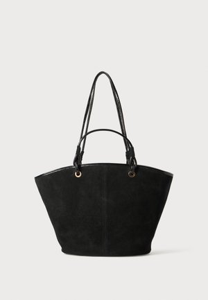 Sac fourre-tout en suede noir avec deux longues poignées lisses noires et quincaillerie dorée. Dispose d'un large ouvert en haut et d'une forme structurée.