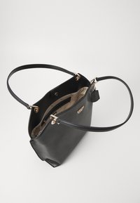 Sort læder tote taske med en struktureret form, guldfarvet hardware, dobbelte håndtag og et mønstret indre foer. Minimalistisk design.