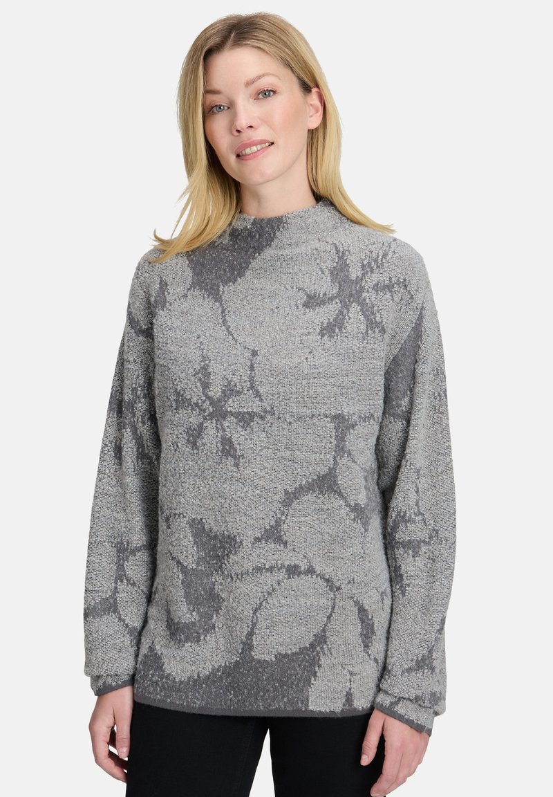 Grauer Strickpullover mit floralem Muster in unterschiedlichen Grautönen, hohen Ausschnitt und langen Ärmeln. Weiche Textur und lässige Passform.