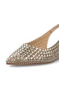 Chaussure ballerine beige à bout pointu avec une texture cloutée, ornée de strass dispersés, de bords festonnés et d'une bride de talon transparente.