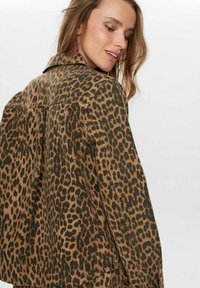 Džínová bunda so leopardím vzorom v hnedej a čiernej farbe. Má golier, dlhé rukávy a stehové detaily pozdĺž švov.