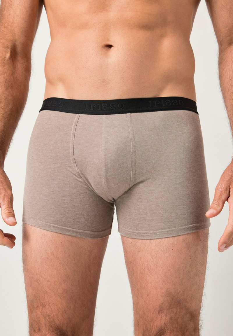 Boxer breves de algodón marrón con una cinturilla elástica negra que presenta texto grabado. La tela tiene una textura suave y un diseño ajustado.