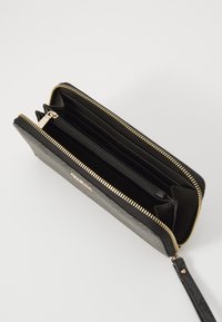 Zwarte leren portemonnee met gouden ritsen, meerdere kaartsleuven en een ritsvak voor munten. Glad textuur, compact rechthoekig ontwerp.