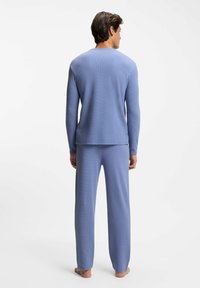 Light blue loungewear set made of textured fabric, featuring a long-sleeve top with a rounded neckline and matching elastic-waist pants.