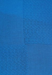 Tessuto blu texturizzato caratterizzato da una combinazione di motivi solidi e perforati, con distinti pezzi in diverse sfumature e texture.