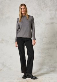 Grijze longsleeve top met een lichte glans, gecombineerd met zwarte straight-leg broek en gestructureerde zwarte enkellaarsjes. Eenvoudig en casual ontwerp.