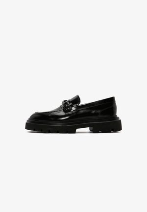 Mocassins en cuir noir avec une semelle en caoutchouc noir épaisse, détail de boucle décorative et finition lisse. Design classique avec des accents modernes.